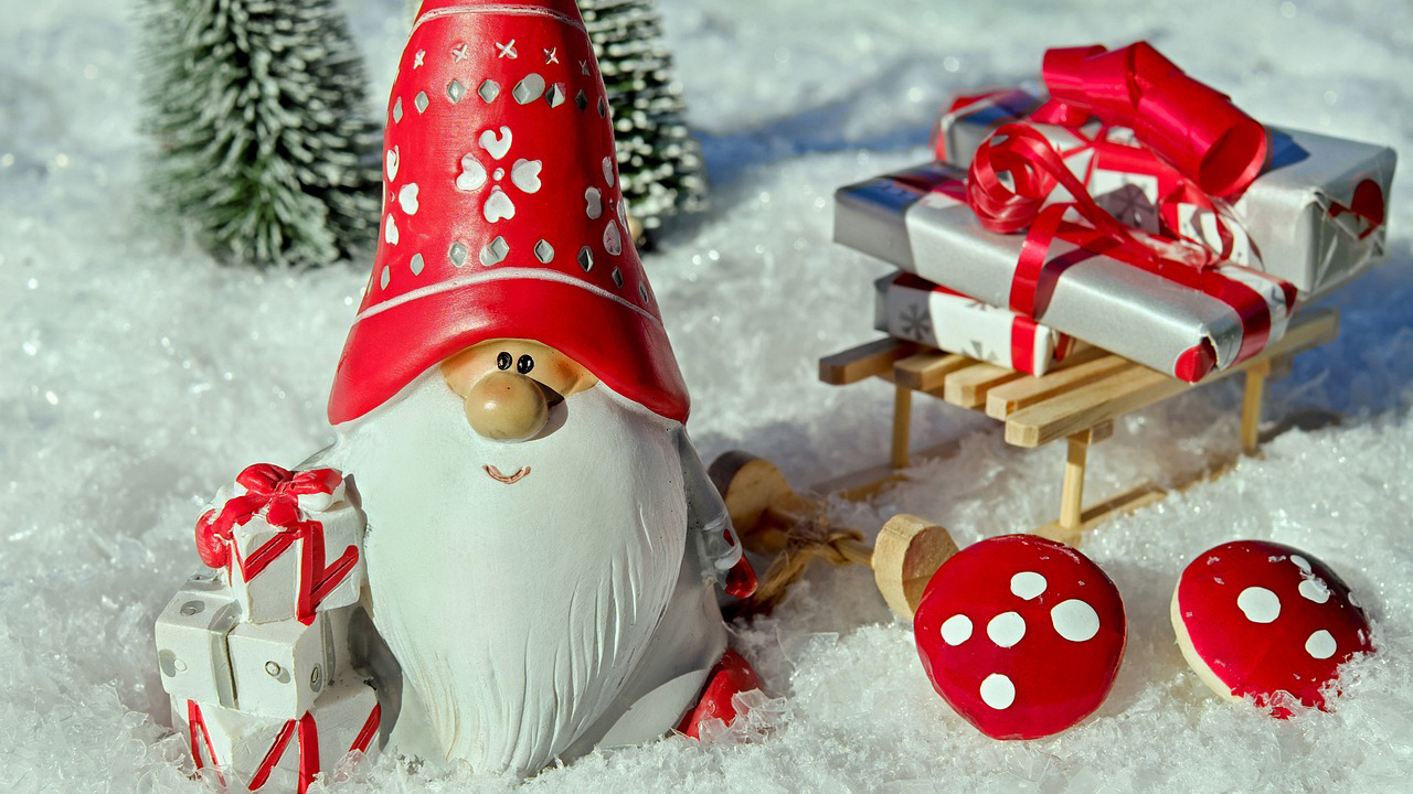 A small plastic "Wichtel" gnome with a sleigh and some presents, smiling friendly