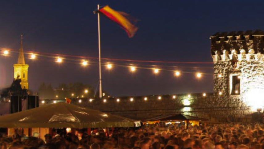 Night shot of a festival crowd with a German flag overhead and some historical buildings