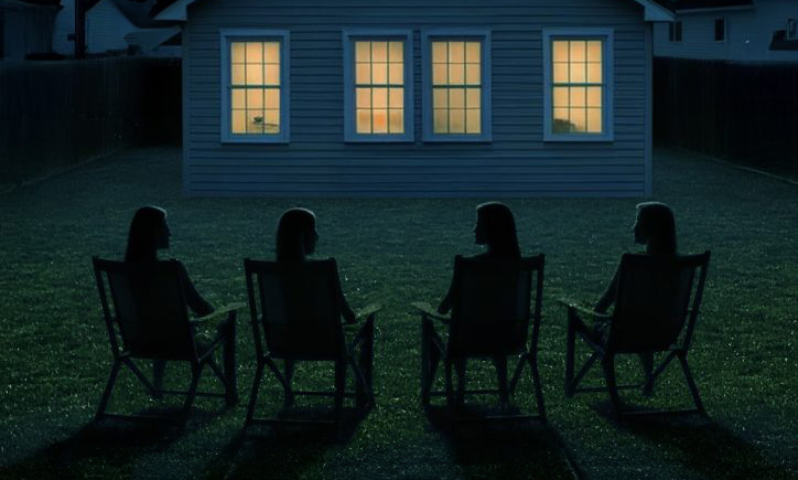 Four women in deckchairs chatting on a warm summer night, facing a house with four glowing windows.
