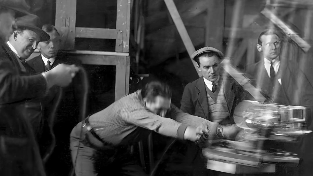 Black-and-white behind-the-scenes photo of a film crew moving the camera in the 1930s