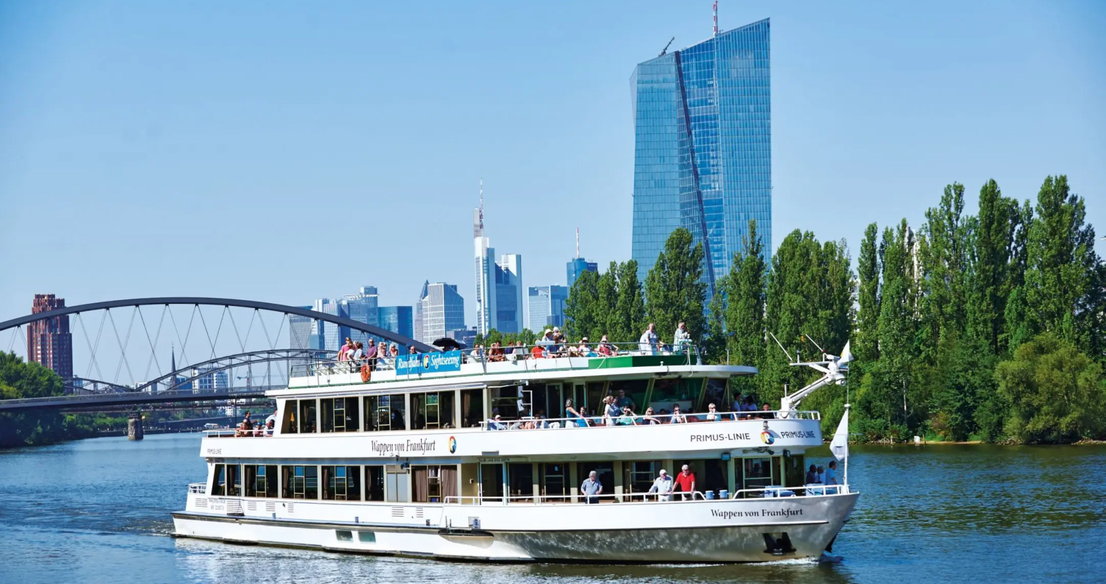 A sightseeing river cruise boat in front of the Frankfurt skyline